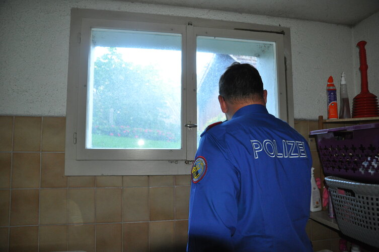 Polizist steht vor einem Fenster