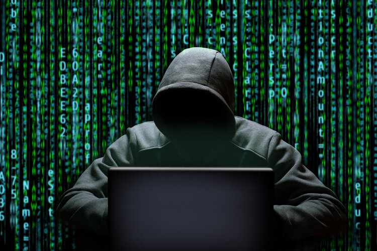 Gestalt mit Kapuze hinter einem Laptop
