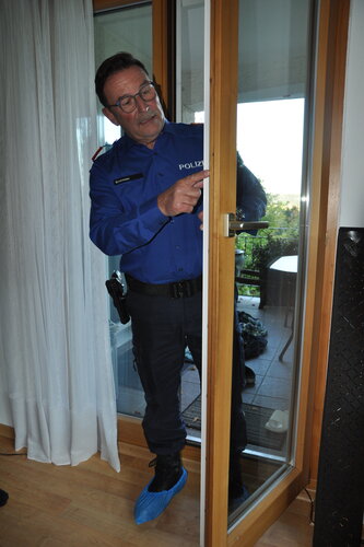 Polizist steht an einer Terrassentür.