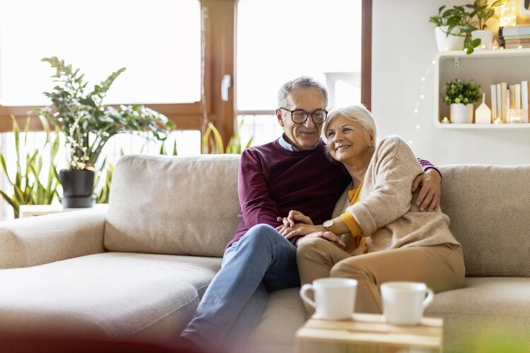 Ein <mann und eine Frau sitzen auf dem Sofa. Sie umarmen sich.